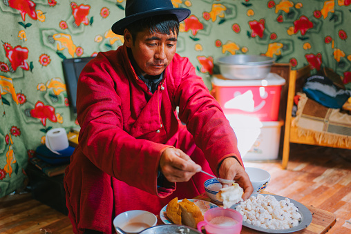Mongolian man enjoying breakfast homemade butter with bread in yurt