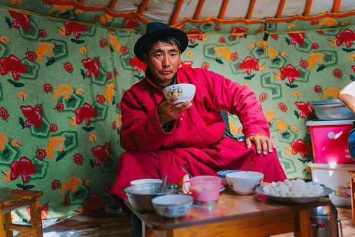 Mongolian man drinking tradition milk tea inside yurt
