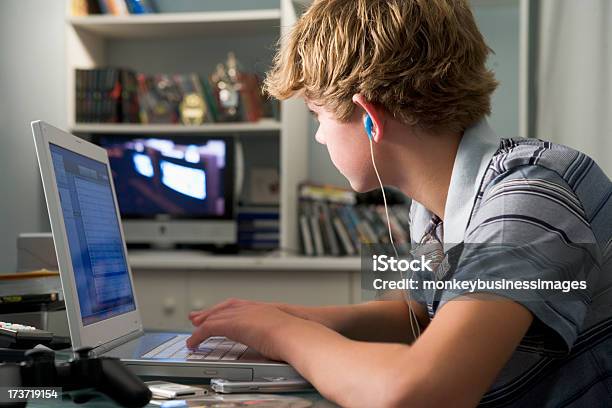 Boy In His Bedroom Using His Laptop Wearing Earphones Stock Photo - Download Image Now