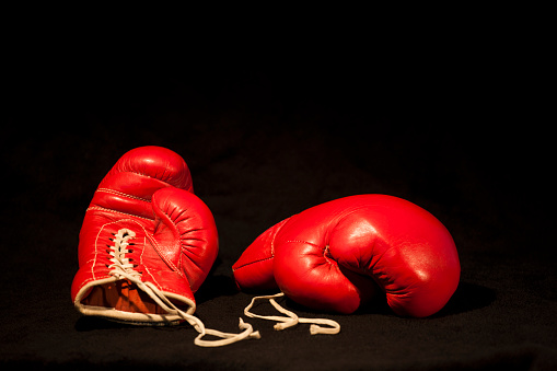 Two red boxing gloves and black bagground.