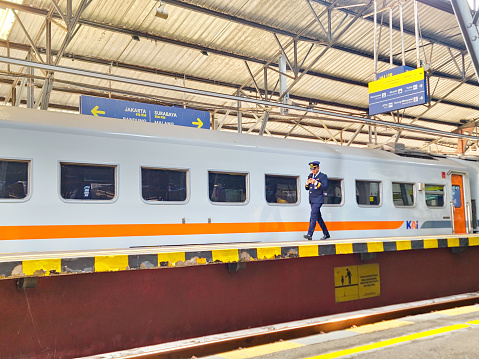 Yogyakarta, Indonesia - 27 September 2023: A dedicated train engineer, clad in their iconic uniform, strides purposefully towards the locomotive of the 