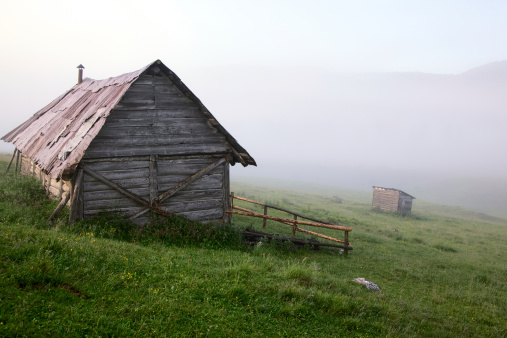 Alpine hut in a misty weather in spring at sunrise