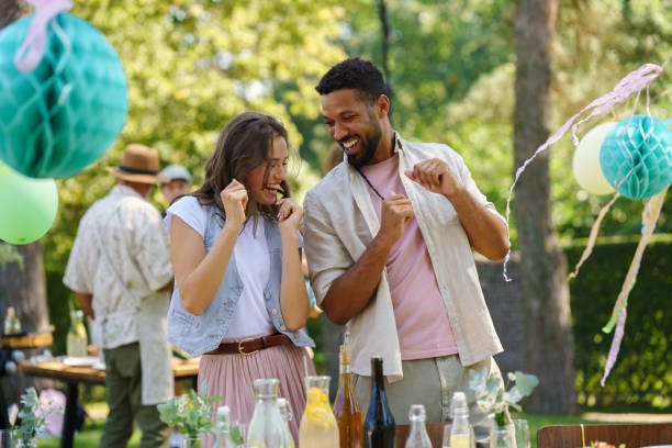 Friends talking and dancing at garden grill party.