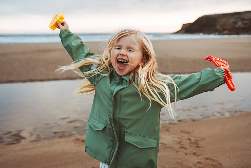 Child girl happy laughing playing outdoor family lifestyle vacations emotional kid smiling walking with toys on the beach