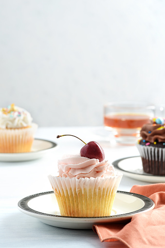 closeup of a cherry buttercream cupcake on a plate with napkin