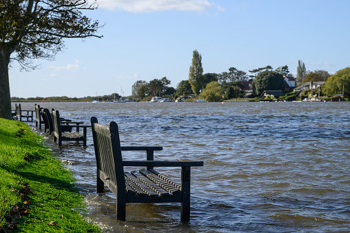 Oulton Broad, Lowestoft, Suffolk. October 14 2023. High tide and heavy rain the night before flooded this urban park with the benches standing in water.