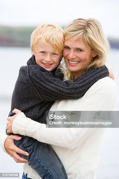 Madre E Hijo En La Playa Sonriendo Retención Foto de stock y más banco de imágenes de 30-39 años - 30-39 años, Abrazar, Acercarse