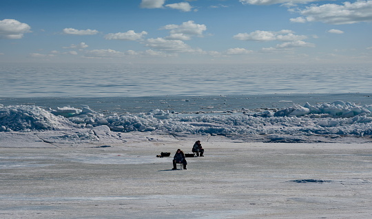 Vzmorie. Russia. March 22, 2023. Ice fishing enthusiasts are fishing on the last spring ice of the Western Pacific Coast on Sakhalin Island.