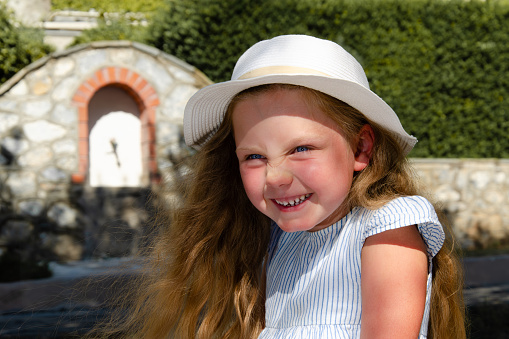 Brown-haired girl of seven wearing a striped blouse and jaunty hat.