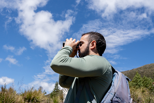 Young man looking through binoculars outdoors