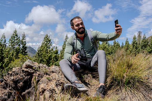 Young man taking a selfie on a mountain peak