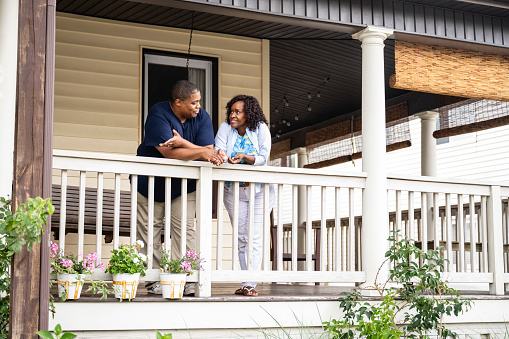 Portrait of happy black family standing on porch of new house and smiling at camera, copy space