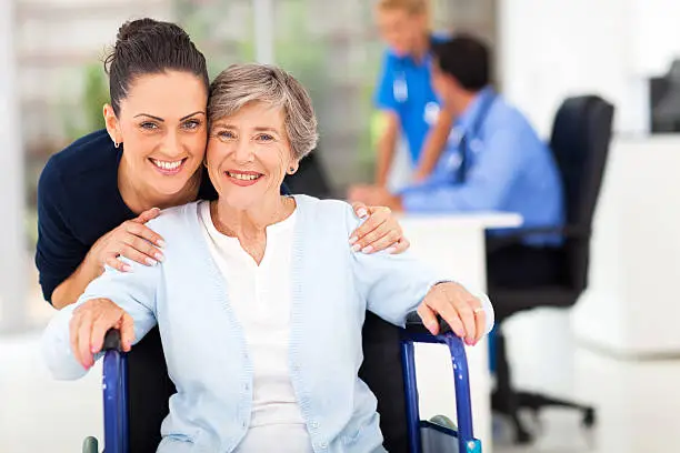 Photo of adult daughter accompanying senior mother visiting doctor