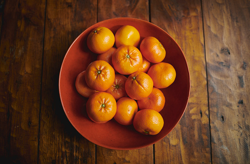 A bowl of tangerines on a wooden table - stock photo