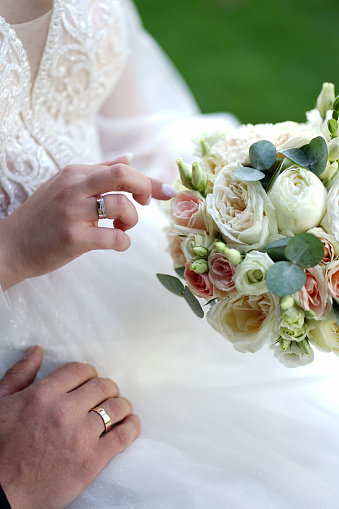 The bride gently touches the flowers of the bouquet. Love and romantic relationships.