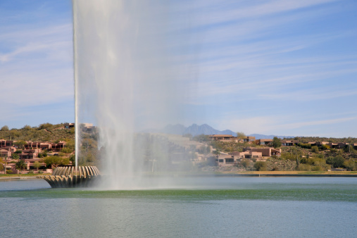 The fountain in the middle of Splash Lake, Fontain Hills, Arizona. The town of Fountain Hills is in the background. Four Peaks Mountain is on the horizon.
