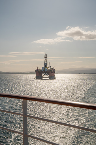 Transocean Leader oil platform at Invergordon during sunset, cruise ship railing in front, vertical shot