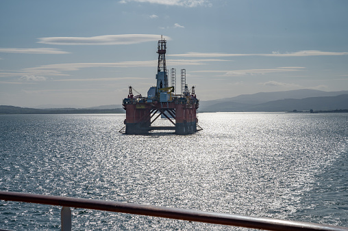 Transocean Leader oil platform at Invergordon during sunset, cruise ship railing in front