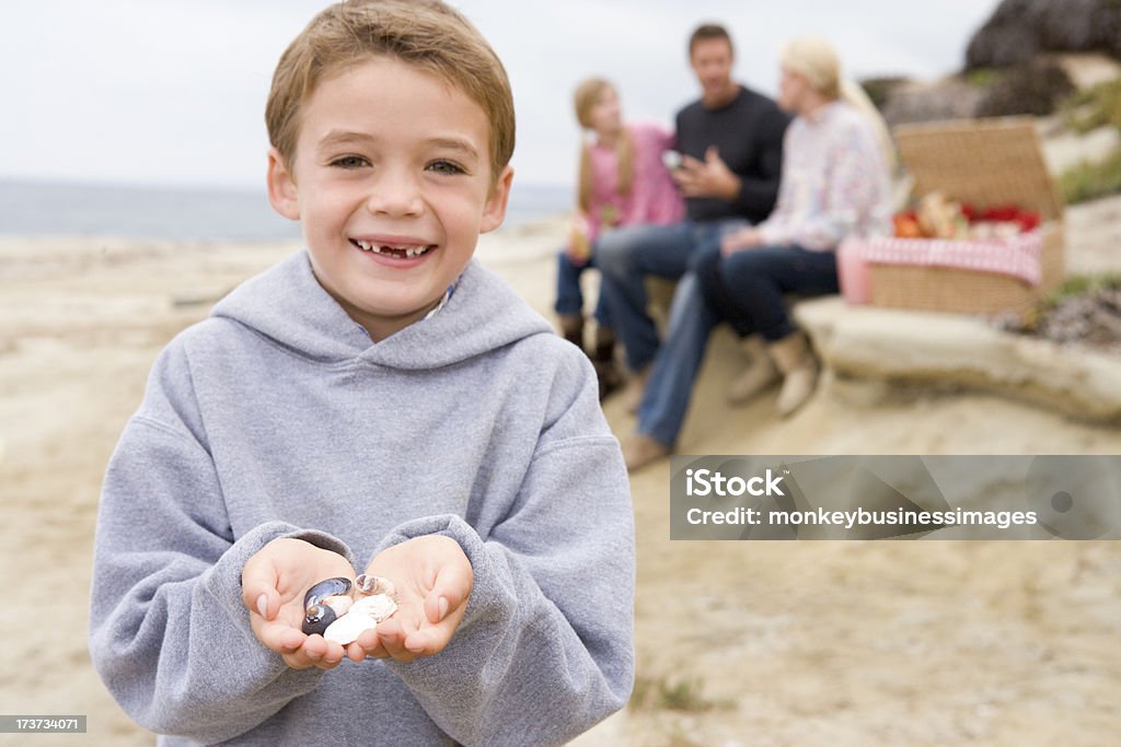 Famiglia in spiaggia con pic-nic sorridente concentrarsi sulla ragazzo - Foto stock royalty-free di Famiglia