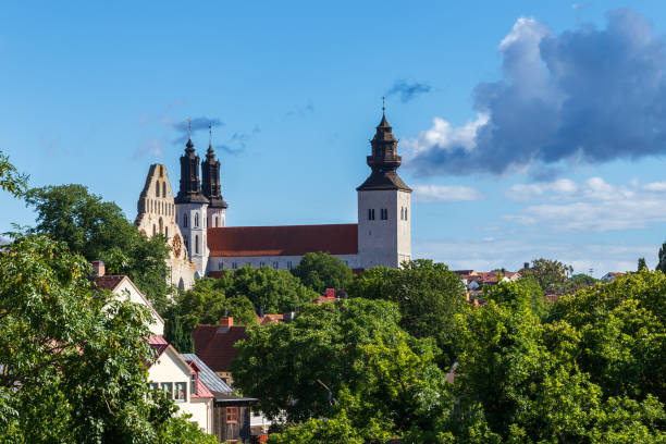Framed by lush green trees, the Sankta Maria Kathedral in Visby serves as a serene and majestic centerpiece in the landscape. The cathedral's architectural beauty is accentuated by the surrounding foliage, offering a harmonious blend of nature and historical grandeur in the heart of Gotland's medieval city.
