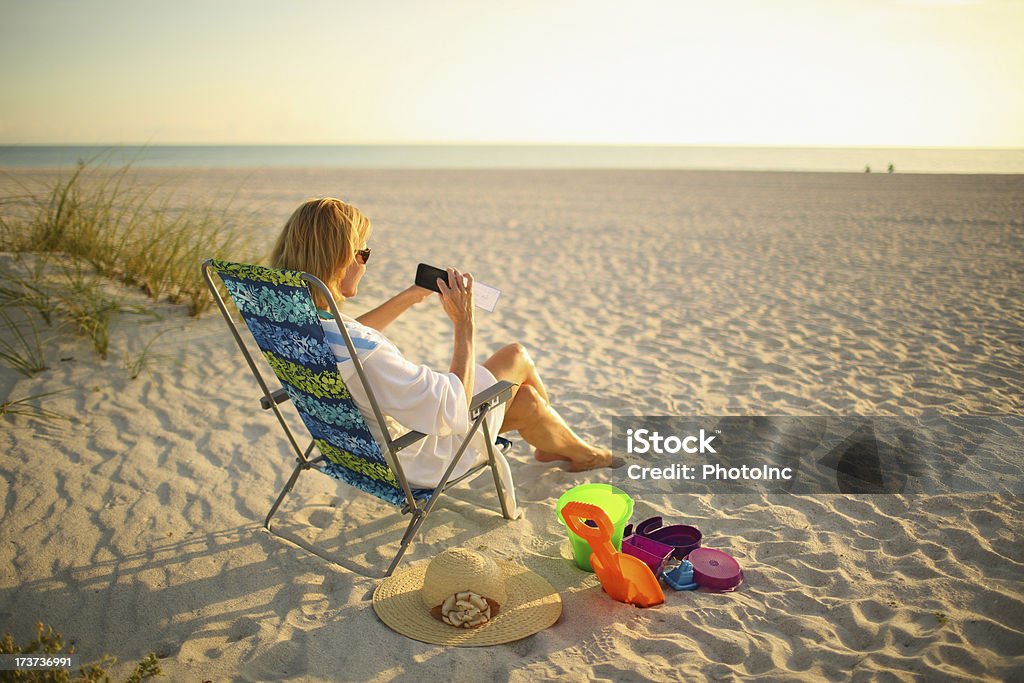 Mature Woman depositing check with mobile phone Mature Woman depositing check with mobile phone while sitting on the beachhttp://i449.photobucket.com/albums/qq220/iphotoinc/MobileBankingLightbox_zps4f4602a2.jpg Bank Deposit Slip Stock Photo