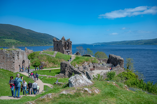 Urquhart Castle with tourist walking around, Loch ness lake in the background, Scotland