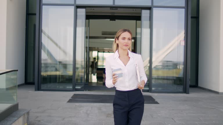 Business woman leaves modern office building and taking a coffee brake