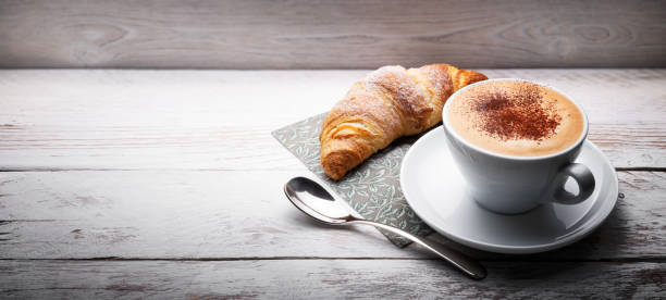 istock Cappuccino and croissant on rustic wooden table, space for text, close-up. 1737399185