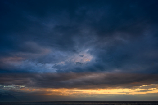 Beautiful sunrise clouds on a summer morning with pinks and blues. Cloudy cloud background and texture. Cluster of clouds with gloomy colors. Sunrise sky landscape travel serene tranquil view with multiple beautiful natural colors.Sea and wave.