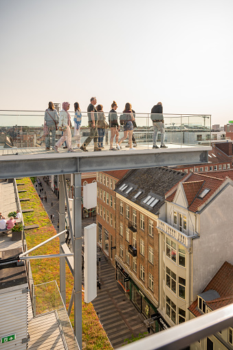 Salling ROOFTOP Roof Garden at Aarhus Denmark with tourists walking on a viewpoint above the city center, vertical shot, in the evening