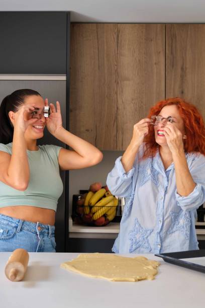 istock Mother and daughter making funny faces with shaped cookies molds. 1737428565