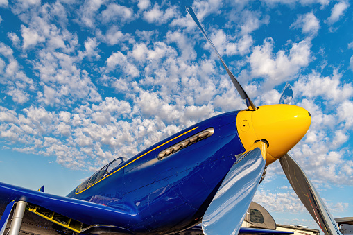 Clouse up of a blue airplane with puffy clouds in the sky