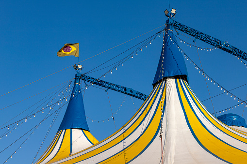 Circus tent blue, yellow and white striped pattern  with brazilian flag, against the blue sky