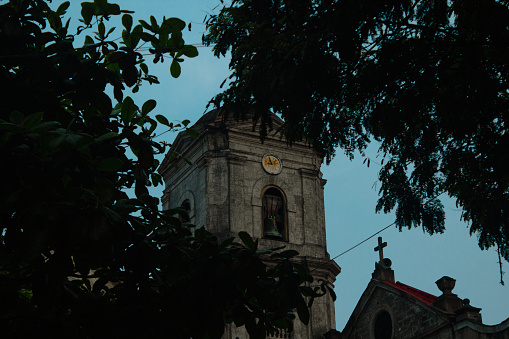 Bell tower of the Church of San Agustín between the trees at sunset.
