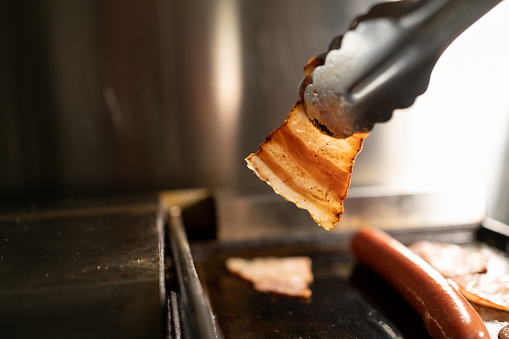 Grilled hot dog and bacon in a street food cafe. Close-up. Copy space