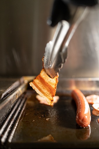 Grilled hot dog and bacon in a street food cafe. Close-up. Copy space