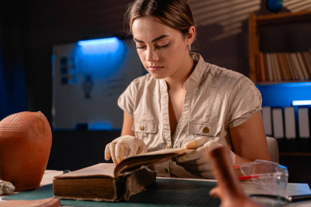 Archeologist reading old book working late night in office and studying amphora