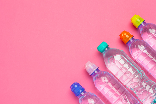 Plastic bottles with pure water on pink background top view space for text
