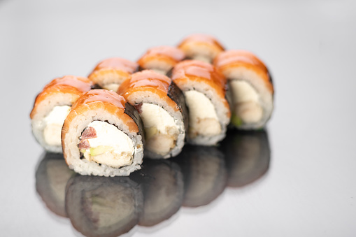 Sushi rolls on white background with reflection, space for text. Japanese food concept