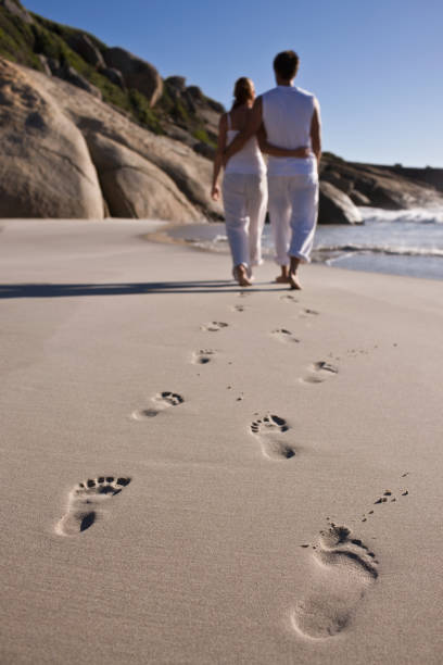 istock Couple walking on beach with footprints in foreground 173748054
