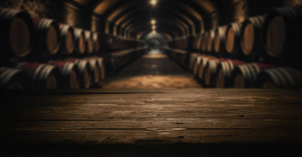 tablero de madera oscura vacío para la exhibición del producto en barriles de vino de bodega borrosos fondo de bodega - wine cellar fotografías e imágenes de stock