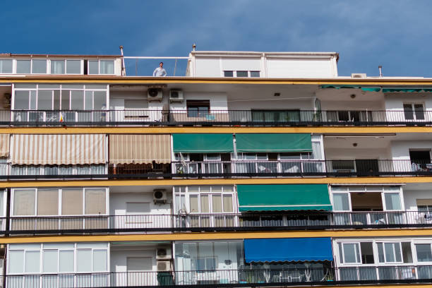 Different windows of multi-storey residential building on blue sky background. Spain, Fuengirola, September 18, 2023