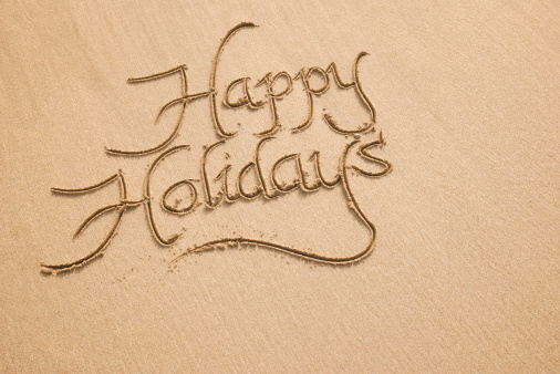 Happy Holidays message is handwritten in golden sand