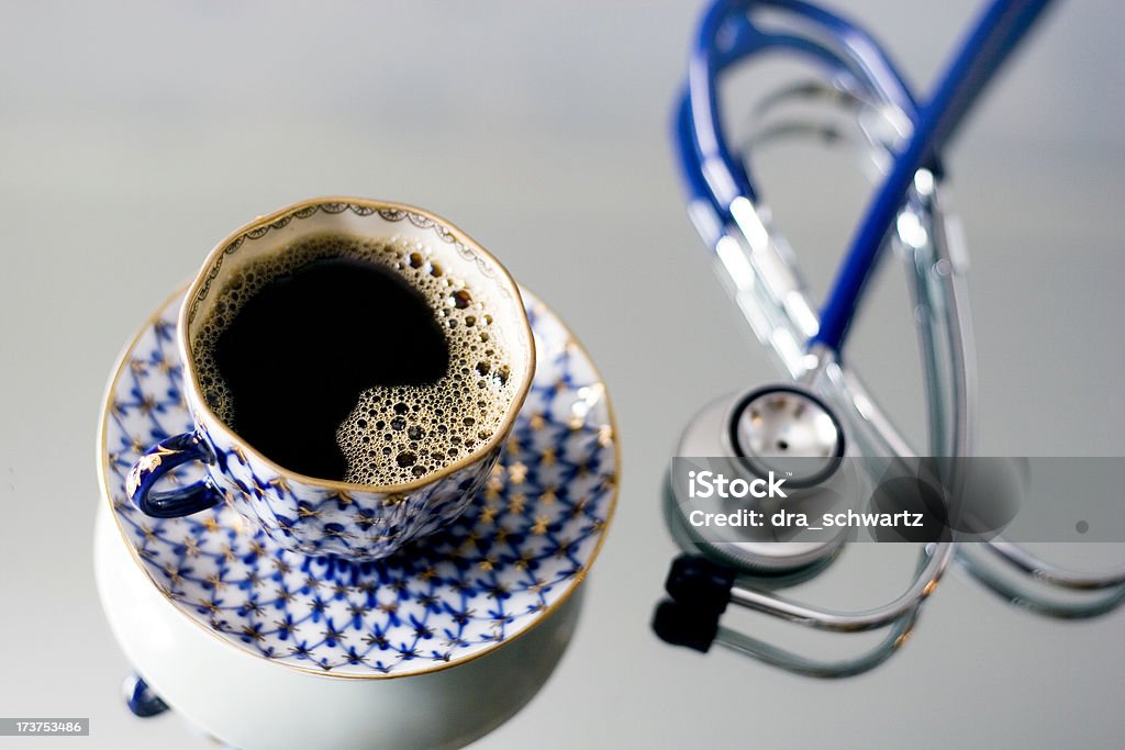 After a night shift Cup of coffee and stethoscope on a reflective surface Benefits Stock Photo