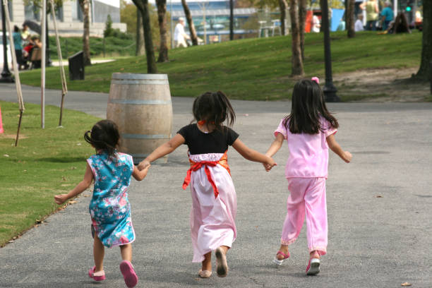Three Chinese little girls running away from the camera and holding hands. Soft focus due to motion.