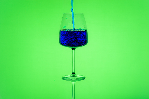 Beautiful cup filling with a blue liquid and a bright green background