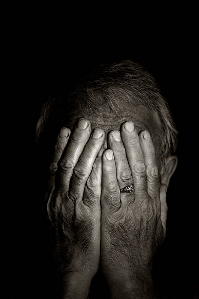 Lost Black and white portrait of a senior man lost in the darkness.  Covering his eyes with his hands.You can find more photographs of this model in schizophrenia photos stock pictures, royalty-free photos & images