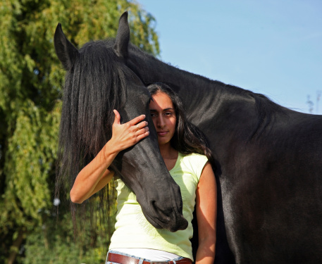 This beautiful dark girl loves her black Friesian horse
