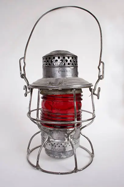 An antique 1925 railroad lantern with a red glass guard.