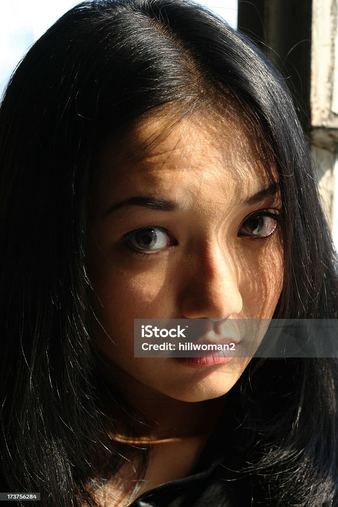 Young Asian Woman - Serious young asian woman looking up in bright sunlight Adult Stock Photo